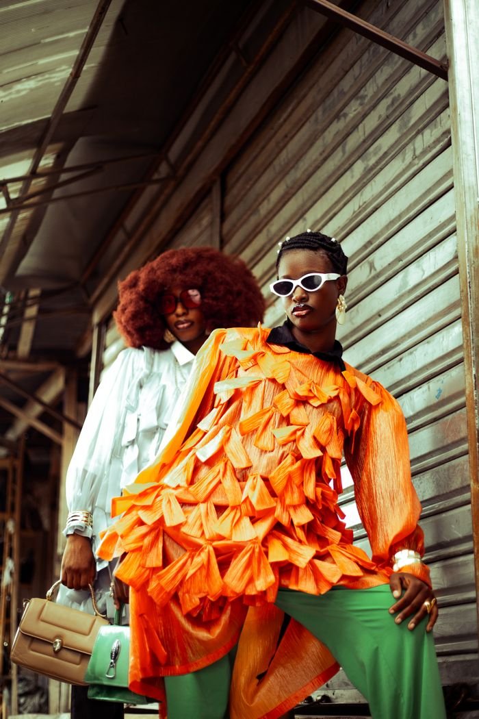 Two stylish adults in bold, colorful outfits pose outdoors, exuding confidence and fashion.