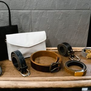 A collection of stylish belts and handbags displayed on a wooden rack in a fashion boutique.