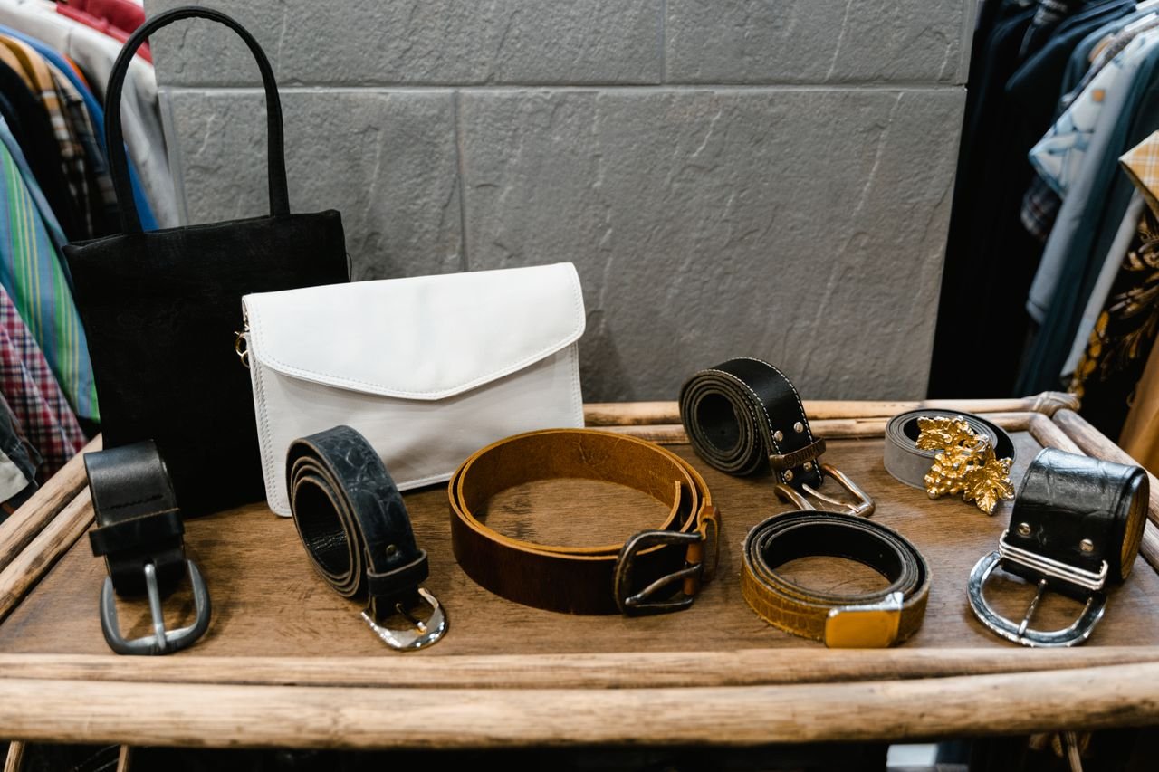 pexels-photo-7679471-7679471 A collection of stylish belts and handbags displayed on a wooden rack in a fashion boutique.